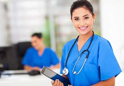 Female nurse wearing blue scrubs smiling