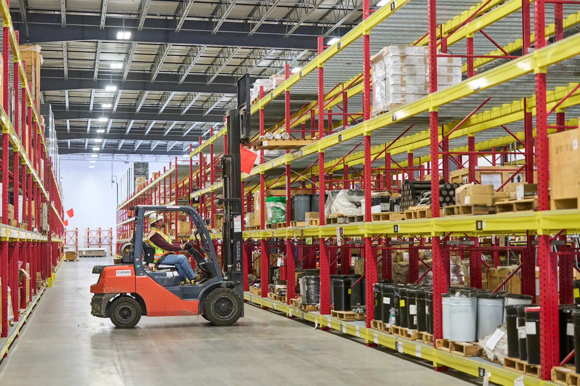 Warehouse worker arranged supplies on a shelf with a forklift.