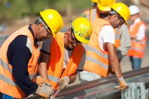 Craft workers assemble a motorway guardrail.