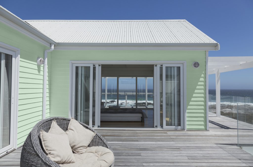 A beach house with  indoor and outdoor view.  House siding painted in light green color  and white roof. 