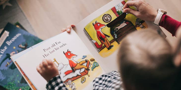 Preschool teacher reading an interactive storybook to a toddler.