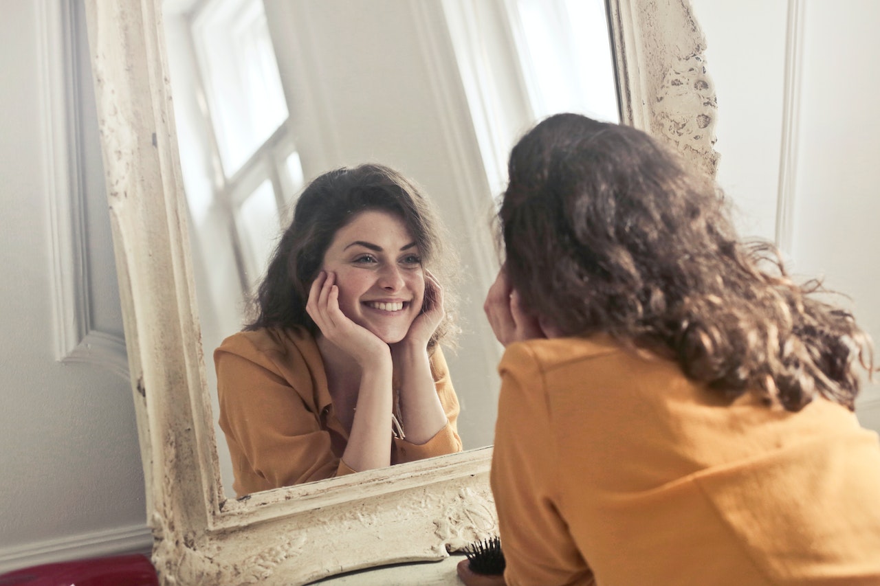 Woman-feeling-confident-looking-in-the-mirror-smiling-how-to-stop-being-self-conscious