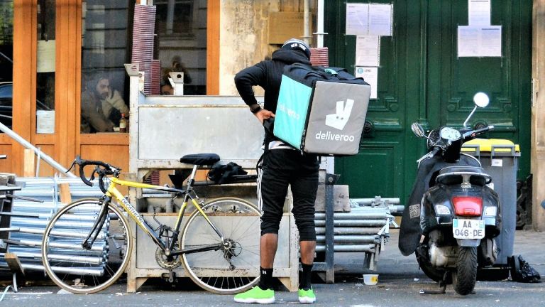 Deliveroo driver waits outside a cafe