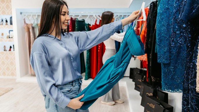 Beautiful young woman shopping for a prom dress in the boutique.