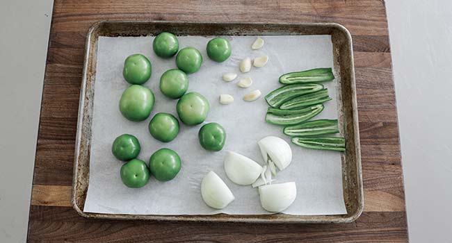 tomatillos, onions, and peppers on a sheet tray