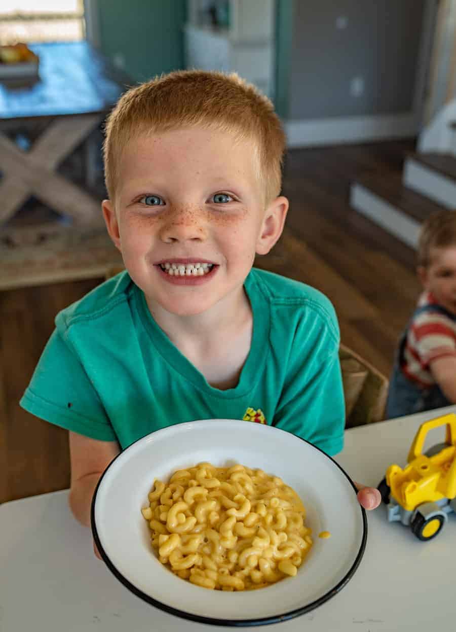 a boy holding a bowl of homemade mac and cheese