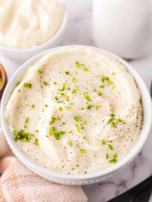 small white bowl with cauliflower mashed potatoes with seasonings on top.