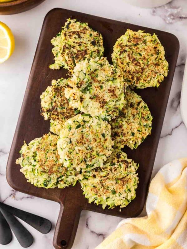 a wooden board with a pile of zucchini fritters.