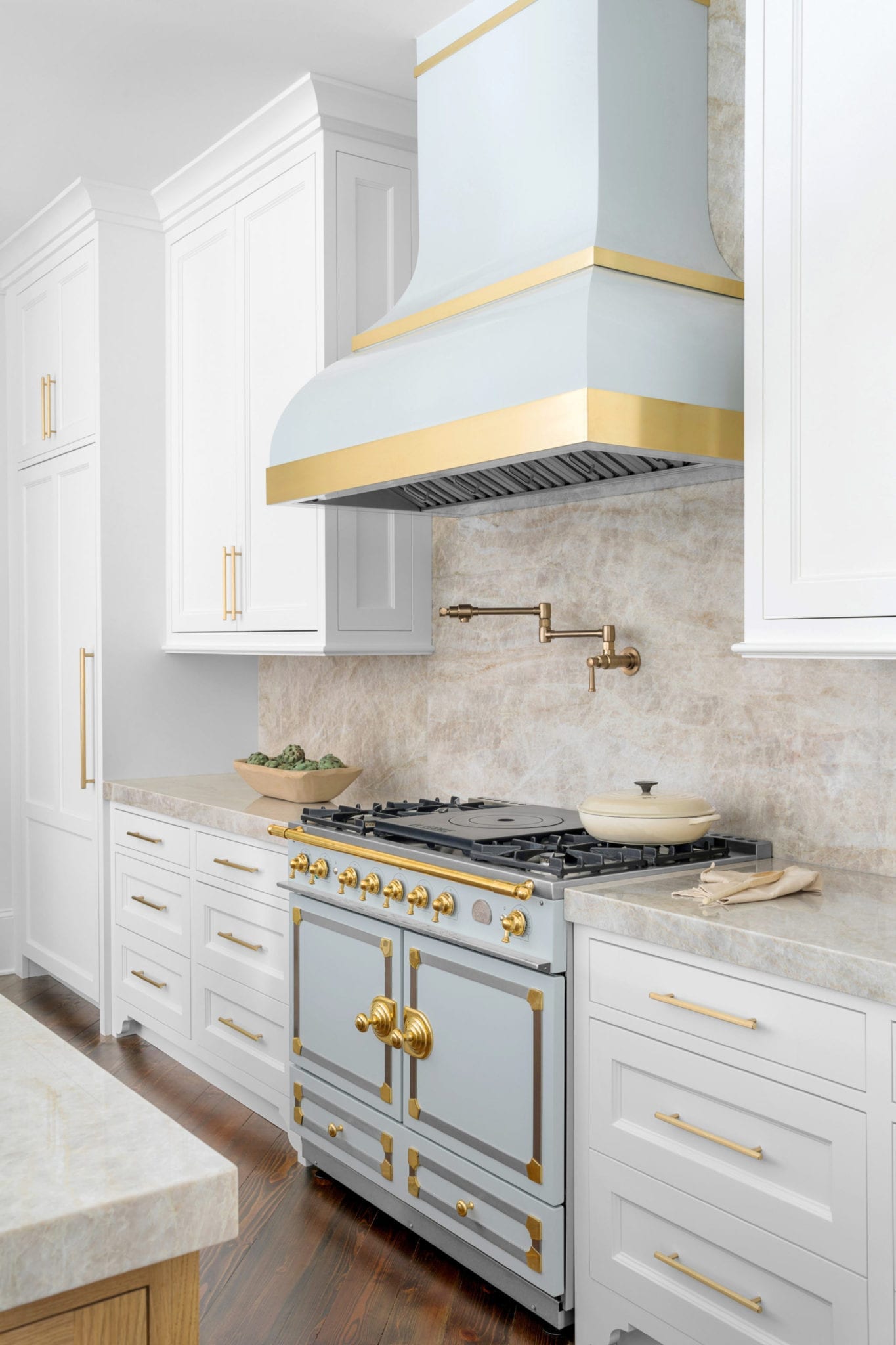 Kitchen Remodel Before and After with LaCornufe Range in blue with custom blue hood, gold pot filler and Taj Majal quartzite countertops and full splash.