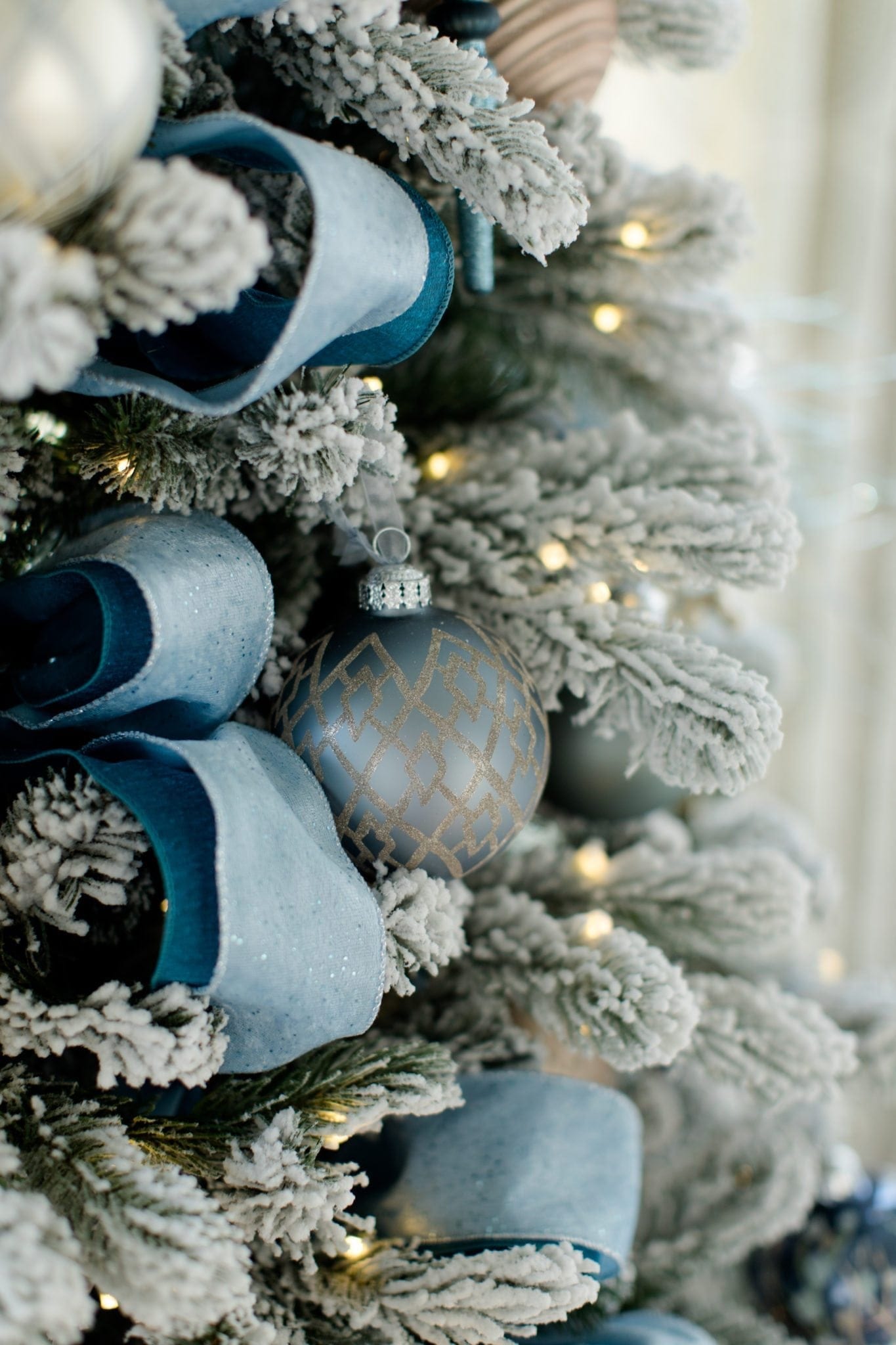 King of Christmas King flock Christmas tree ideas on a blue and silver Christmas tree with blue white and silver Christmas decorations.