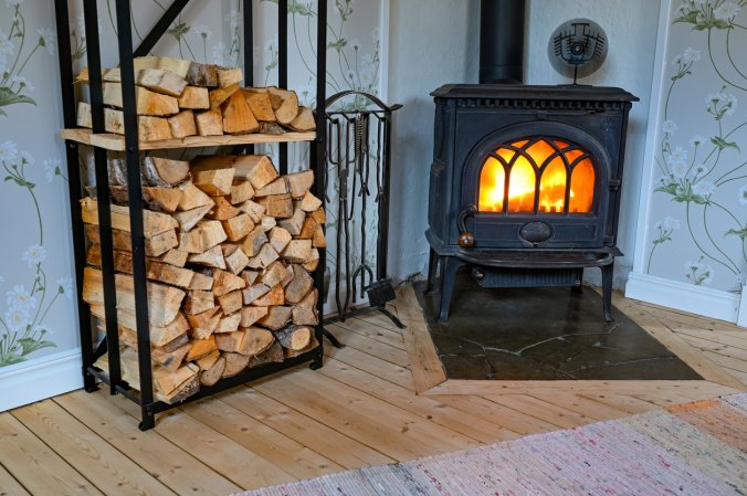 A wood stove fan on top of a wood-burning stove full of flames.