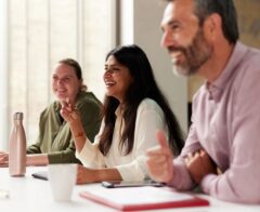 Businesspeople laugh as they engage with a presentation.