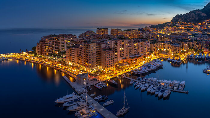 lightened buildings near the shore with yachts