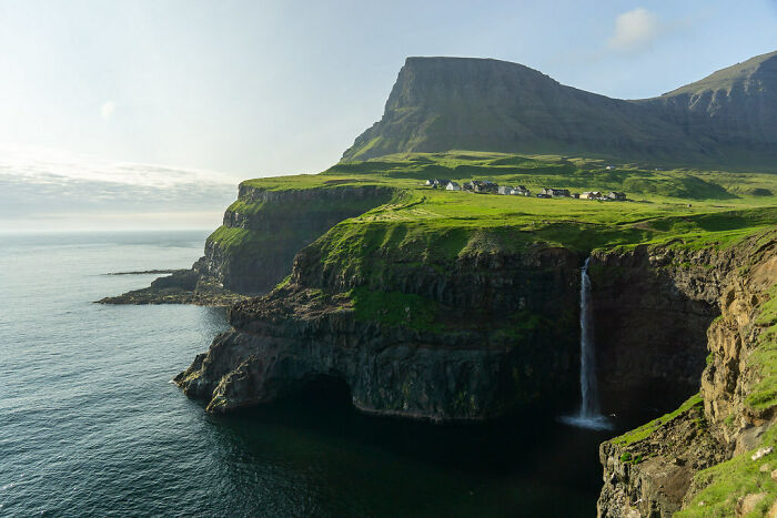 green rocks with a waterfall near the sea