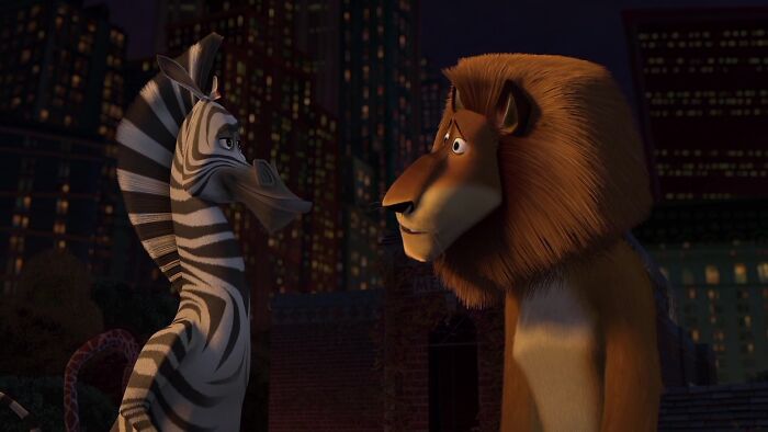 Zebra and lion iconic best friend duo from animated film in a cityscape setting at night.