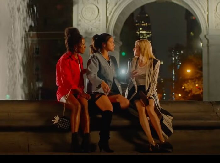 Three women sitting together at night, embodying iconic best friend duos, with city lights in the background.