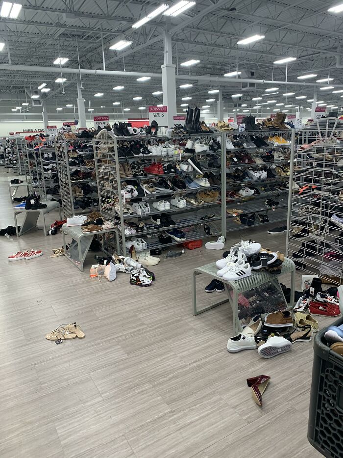 Messy shoe aisle in a store with disorganized footwear scattered on shelves and floor, illustrating lazy infuriating people.