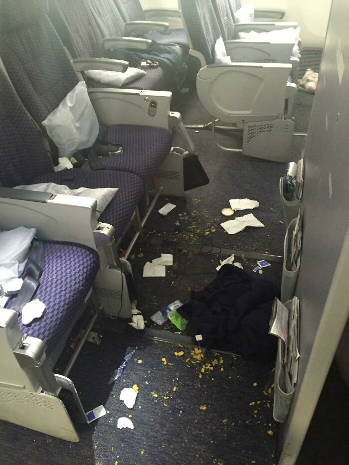 Messy airplane seats with trash scattered, showcasing lazy-infuriating-people's behavior.