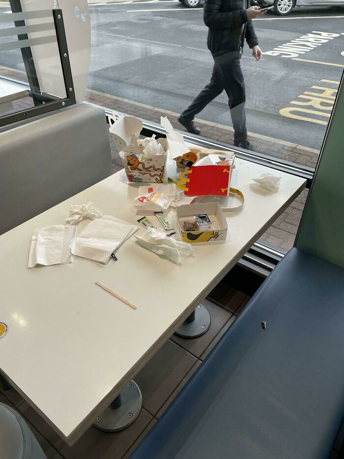 A messy fast-food table with empty food boxes and napkins left behind.