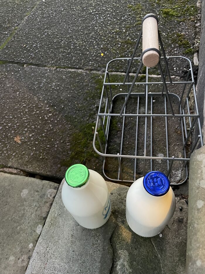 Milk bottles left outside on a doorstep next to an empty metal carrier, symbolizing lazy-infuriating-people behavior.