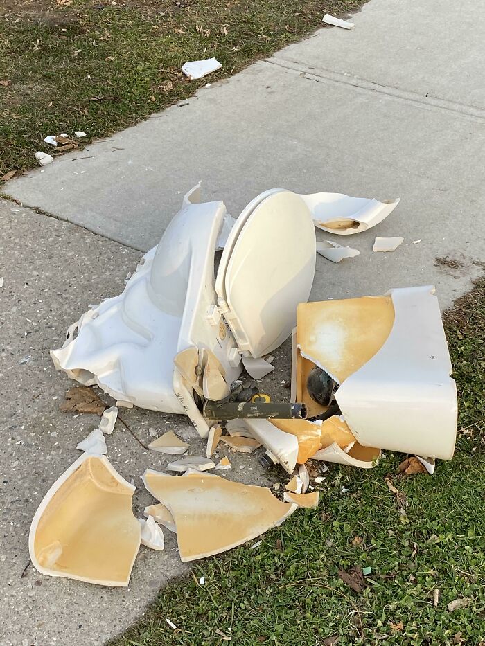 Broken toilet left on sidewalk, displaying lazy-infuriating behavior.