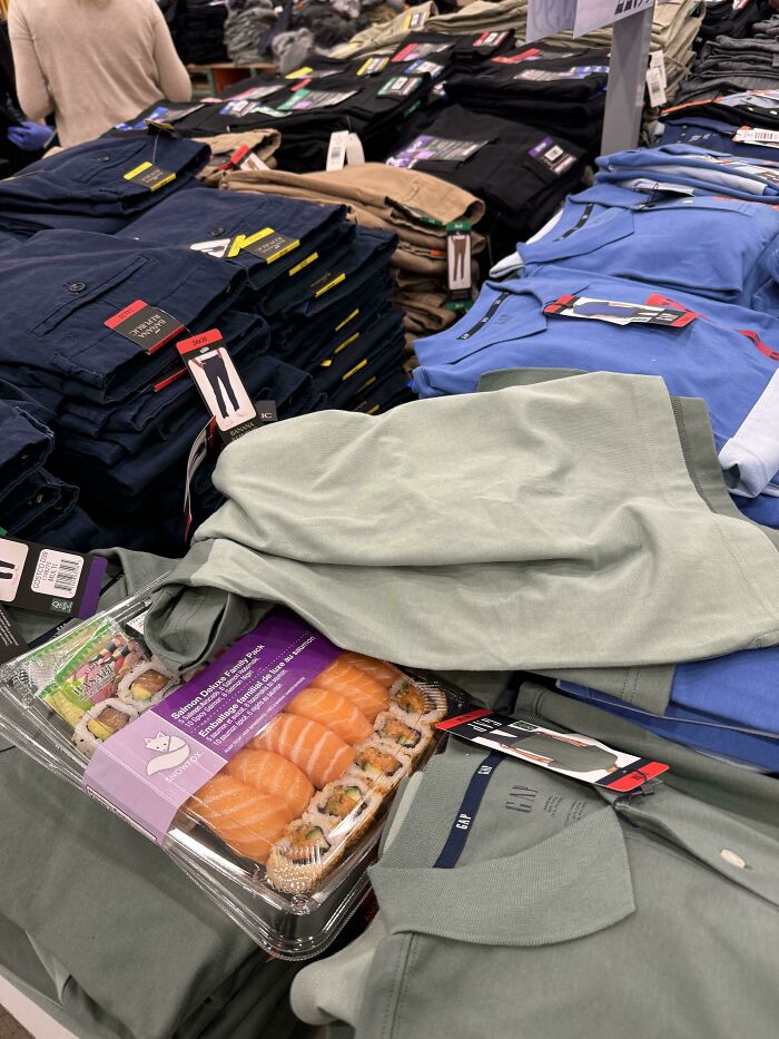 Sushi box placed on top of folded clothes in a store, depicting lazy-infuriating-people behavior.