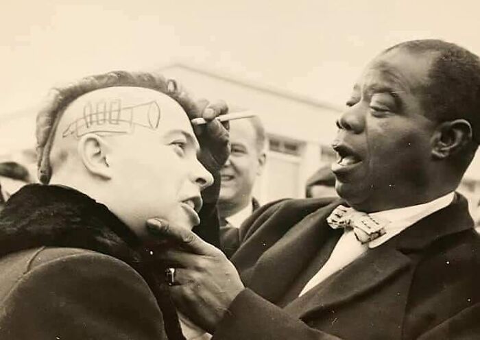 A man is getting his head painted with a rocket design. A historical moment captured in black and white.