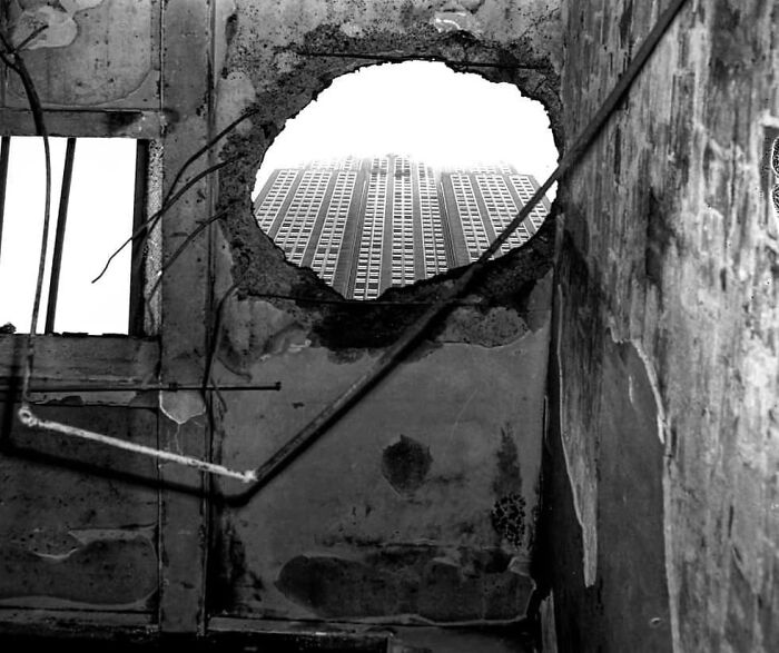 View of a modern skyscraper through a crumbling wall, illustrating the concept of learning from the past for the future.