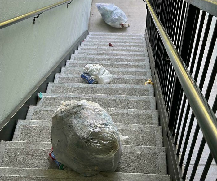 Trash bags left on stairs, showcasing lazy behavior that infuriates others.