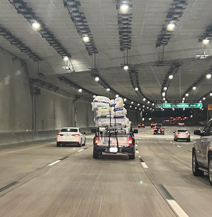 Truck overloaded with unsecured items drives recklessly in a tunnel, showcasing lazy and infuriating people on the road.