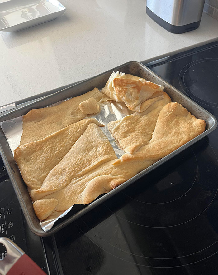 Baked dough spread unevenly on a tray, showcasing a lazy cooking attempt on a kitchen counter.