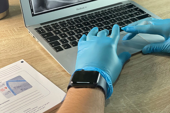 Hands wearing gloves using a laptop, with a document nearby, addressing tasks like "wash rice."