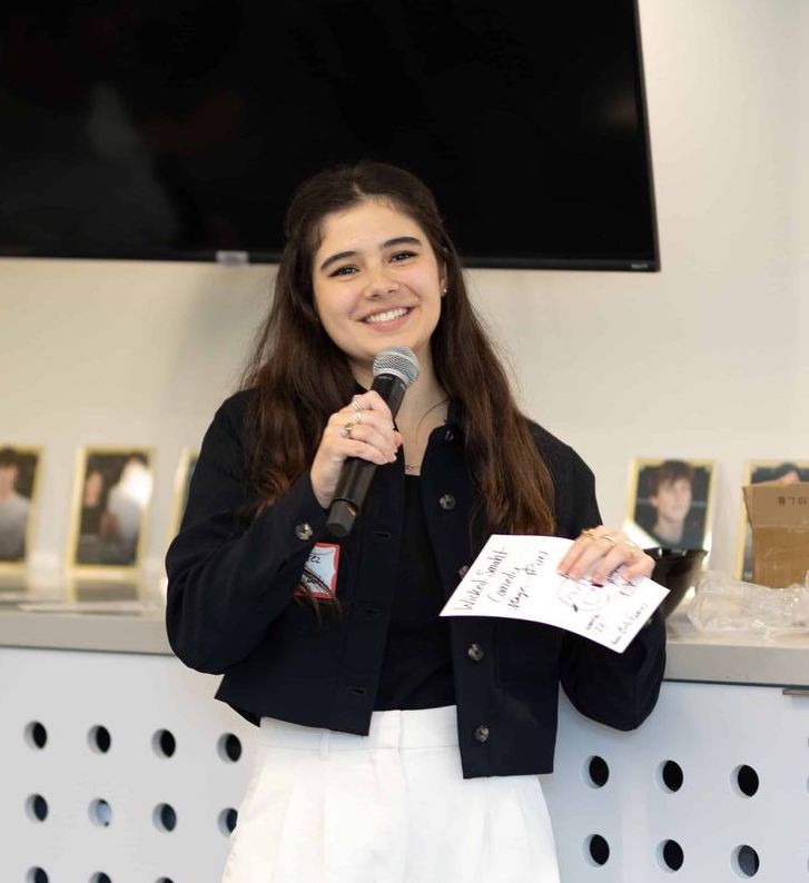 A woman standing with a microphone giving a presentation