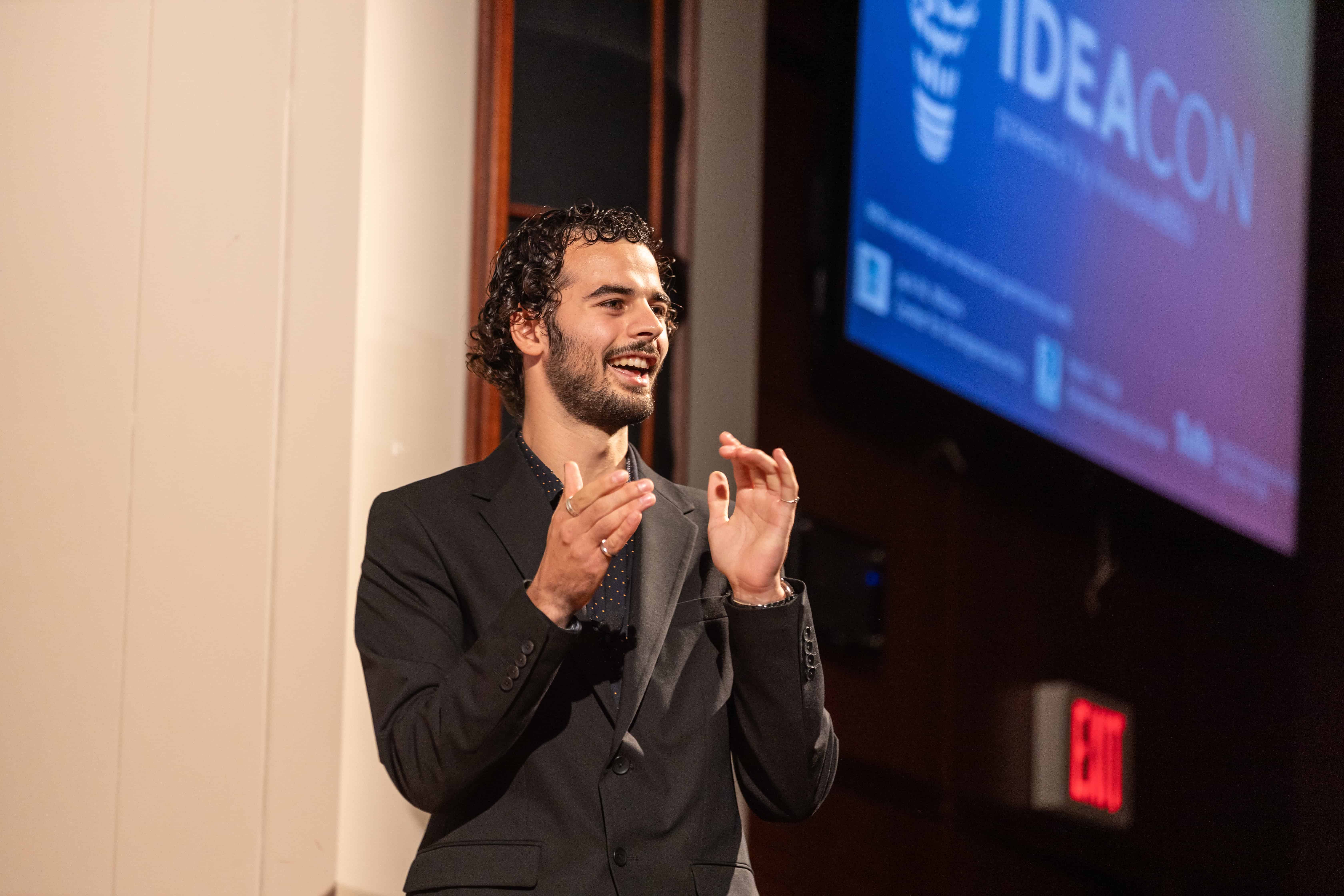 Man clapping and smiling on stage at a large event