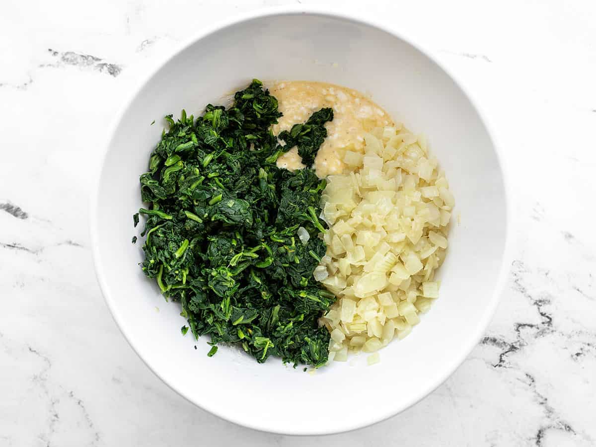 Spinach and onions added to the cheese mixture in the bowl