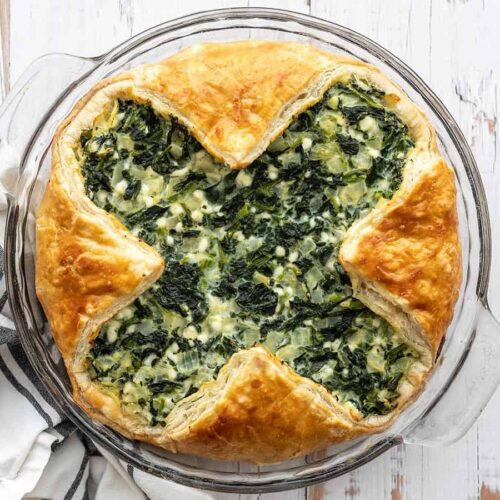 Overhead view of spinach pie in the glass pie dish on a wooden surface