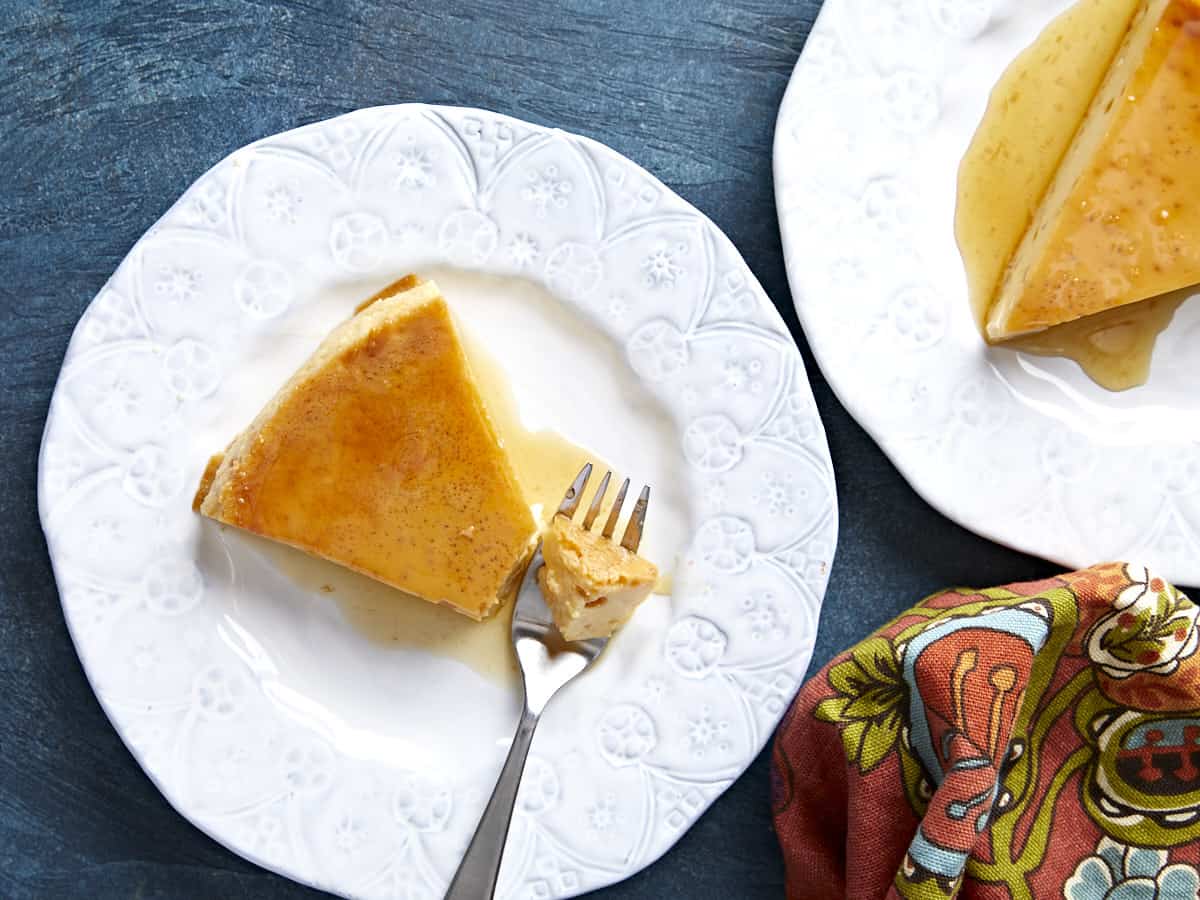 Two plates with slices of flan, a fork with a piece on the end.