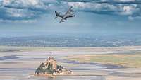 Ein Flugzeug fliegt über die Insel Mont-Saint-Michel.