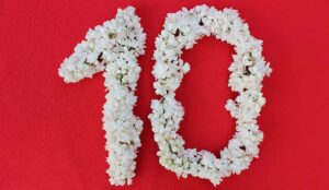 The number 10 is written in white lilac flowers on a red background