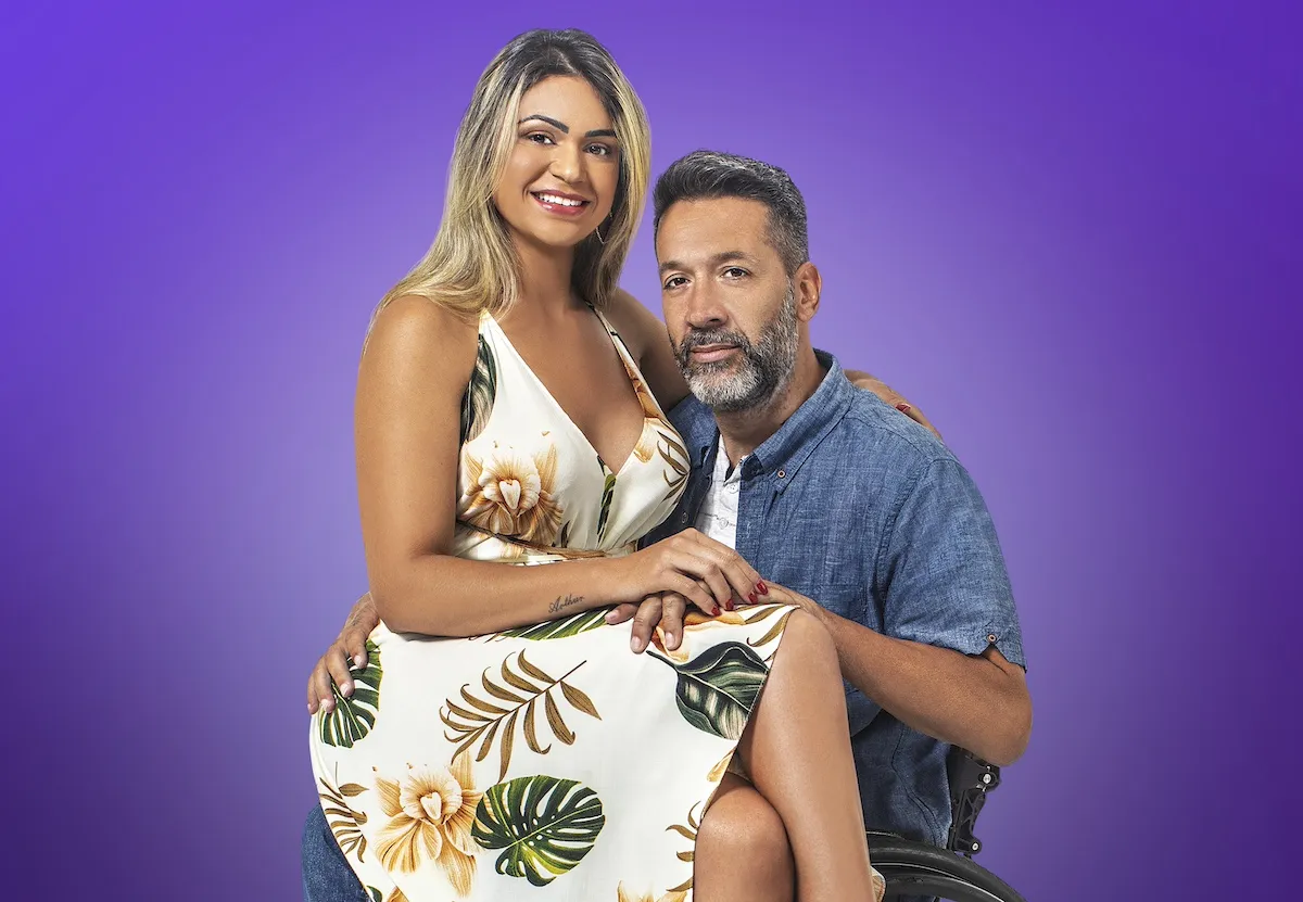 Ingrid sitting on Brian's lap in promo shot on a purple background for '90 Day Fiancé: Before the 90 Days' Season 7