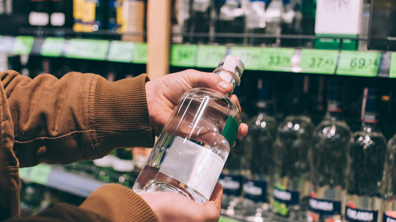 Man picking up vodka in supermarket