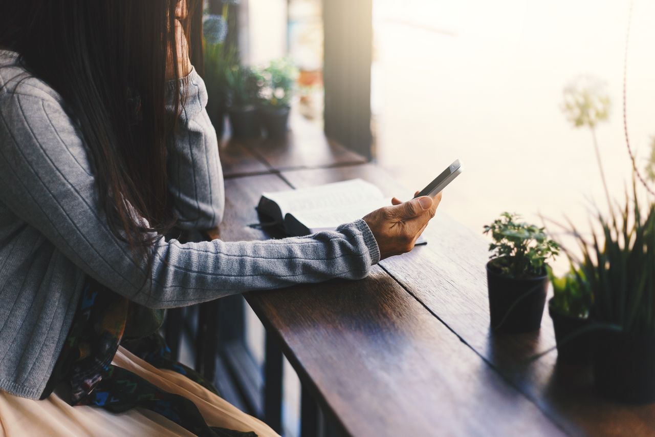 a woman by a window holding a phone