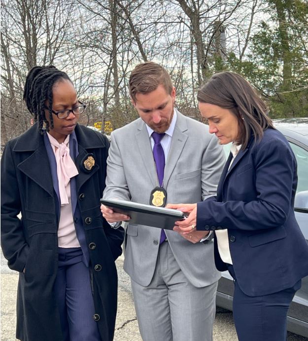 Three Army CID Agents, two female and one male, review evidence on a tablet at an incident scene