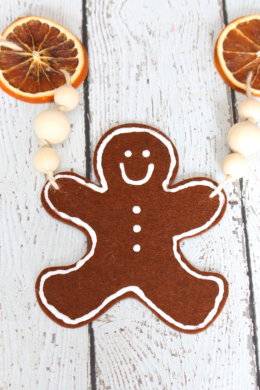 Cute DIY felt gingerbread man garland with dried oranges and wood beads.