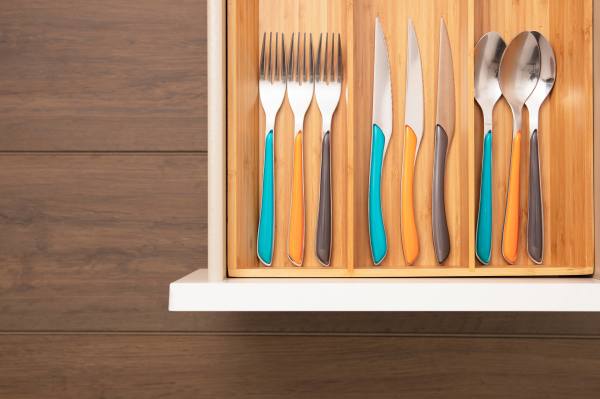 A neatly organized cutlery drawer with forks, knives, and spoons arranged in separate compartments.