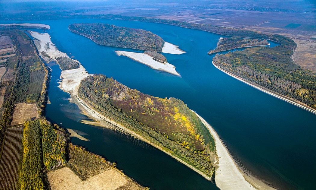 A river flows through lush forest and farmland, bending in the distance