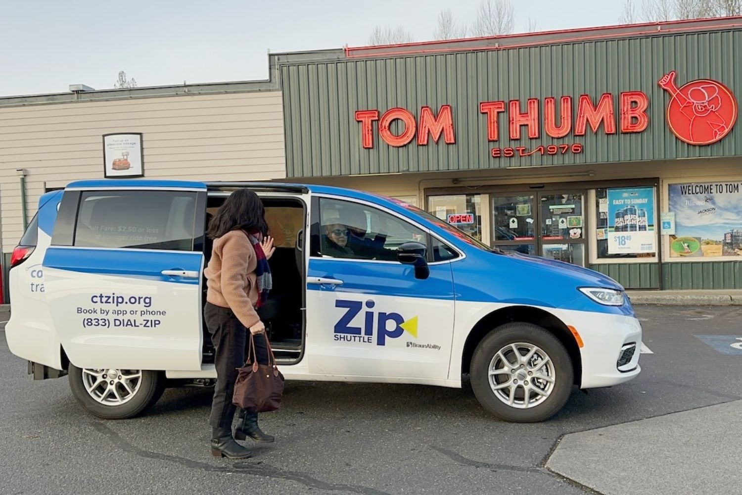 A woman waves at the driver of a Zip Shuttle van before entering the Tom Thumb store in Lake Stevens.