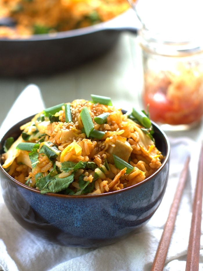 Bowl of Kimchi Fried Rice with Chopsticks and a Jar of Kimchi in the Background