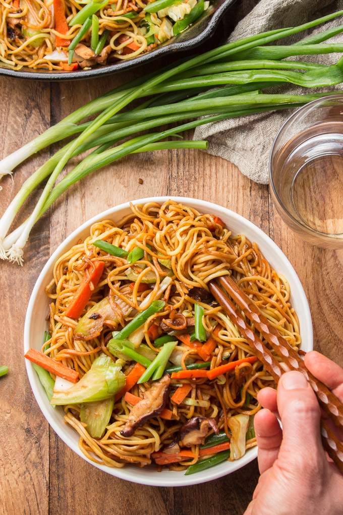 Hand Using Chopsticks to Grab a Bunch of Noodles from a Bowl of Vegetable Chow Mein