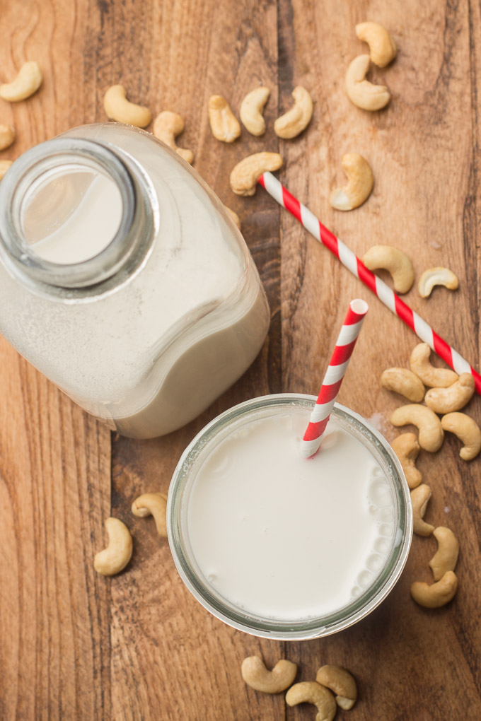 Glass and Bottle of Cashew Milk on a Wooden Table with Cashews